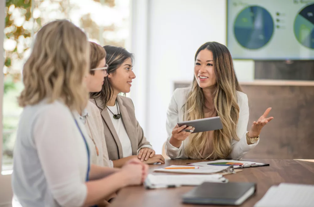 Consultante en marketing échangeant avec des clients lors d’une réunion, illustrant la collaboration autour de l’utilisation d’un CRM en Wallonie.